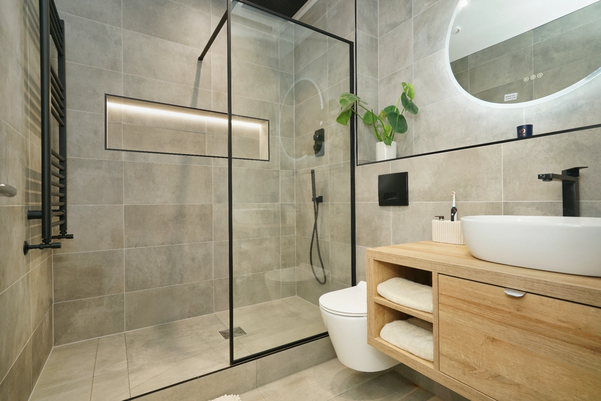 Grey tile shower with black-framed glass panel